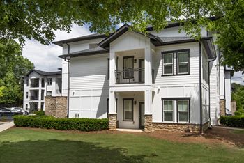 A white two-story house with a stone pillar and a black door.